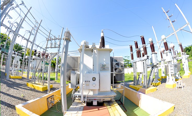 Row of power lines and substation equipment against the sky